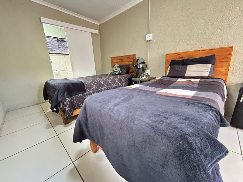 A bedroom featuring tiled flooring and a sliding door leading to an adjacent bathroom, with neutral wall finishes.