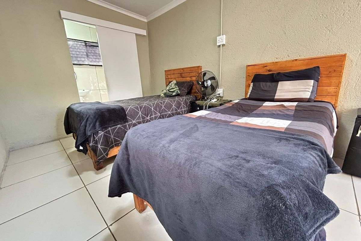 A bedroom featuring tiled flooring and a sliding door leading to an adjacent bathroom, with neutral wall finishes.
