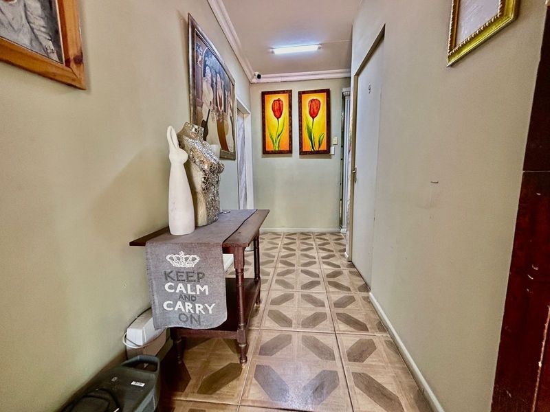 A functional hallway featuring tiled flooring and coving, providing access to various rooms within the apartment.