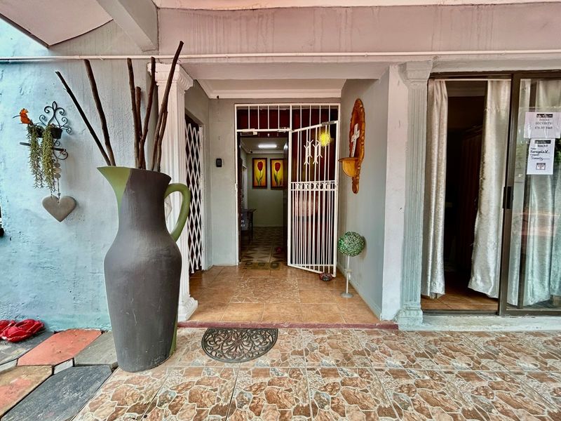 Covered entrance area featuring tiled flooring, a security gate, and access to the main interior living space.