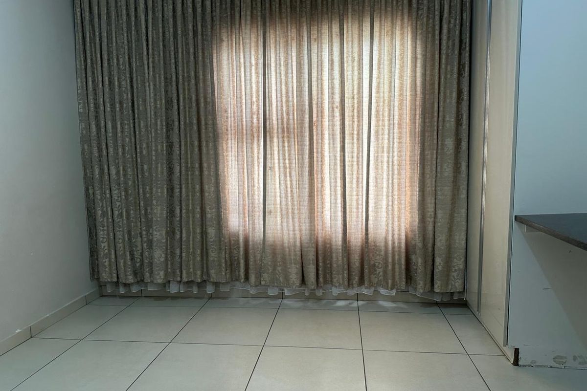A vacant bedroom featuring neutral tiled flooring and built-in cupboard storage, offering a blank canvas for personalization.