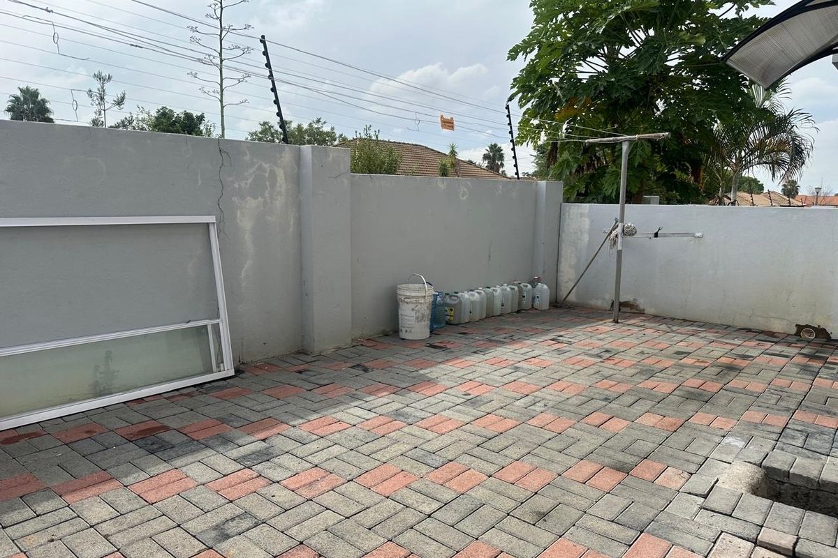 A paved rear courtyard area featuring a boundary wall with electric fencing and a fixed washing line.