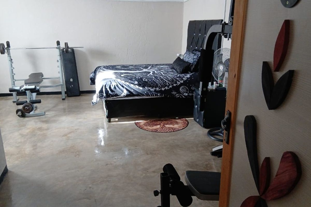 A bedroom featuring polished concrete flooring, currently utilized as a multi-purpose space with gym equipment.