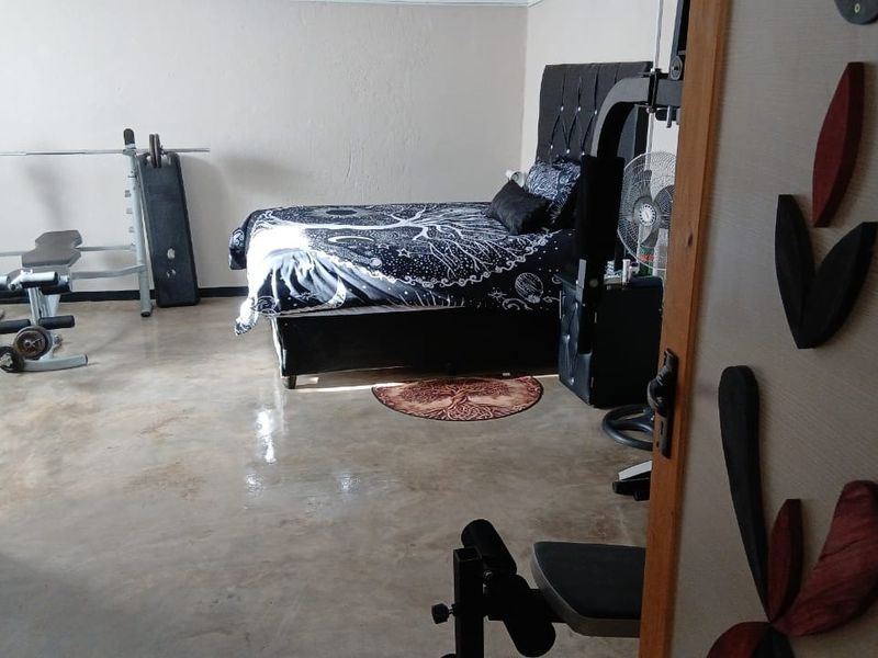 A bedroom featuring polished concrete flooring, currently utilized as a multi-purpose space with gym equipment.