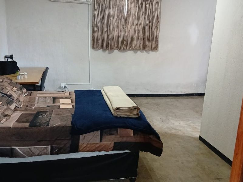A bedroom featuring an air conditioning unit and basic finishes, currently showing signs of wear on the walls and flooring.