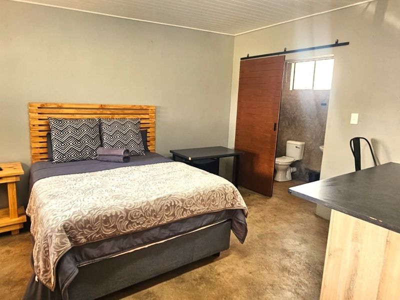 Open-plan studio apartment featuring a combined bedroom and kitchen area with a private en-suite bathroom accessed via a sliding barn door.
