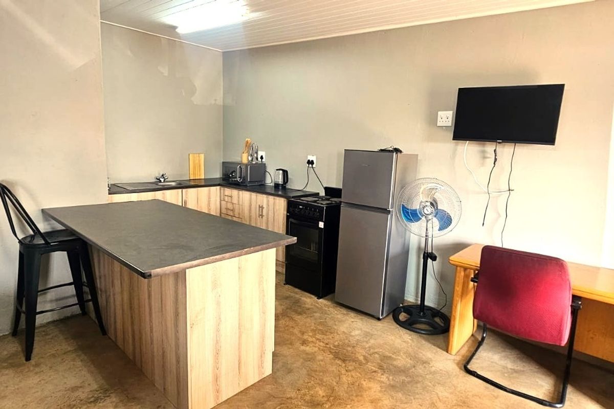 Open plan kitchen area featuring wood-look cabinetry, a breakfast bar, and a functional layout with basic fixed appliances.