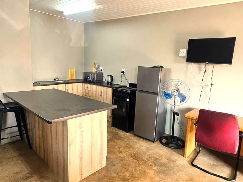 Open plan kitchen area featuring wood-look cabinetry, a breakfast bar, and a functional layout with basic fixed appliances.