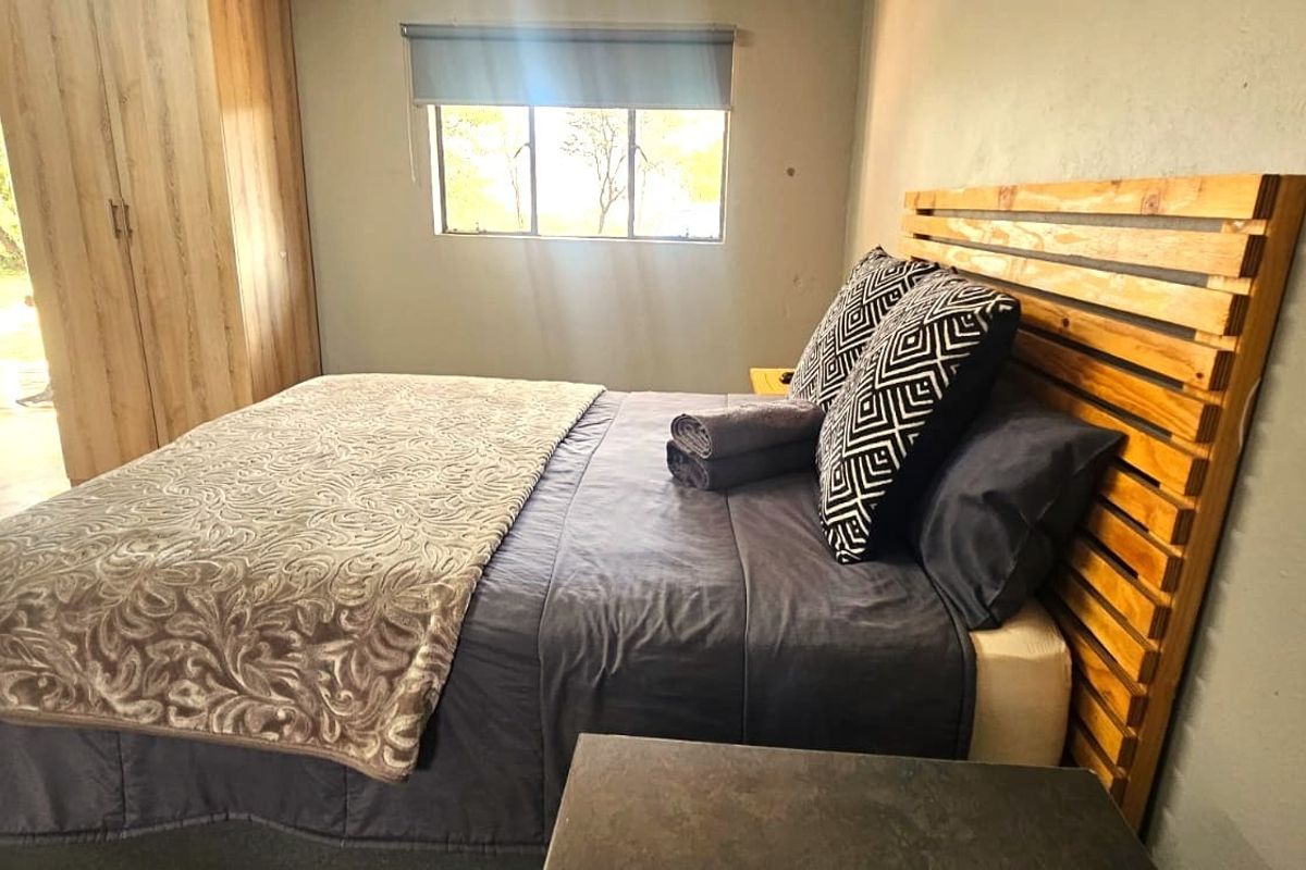 A functional bedroom featuring a built-in wardrobe, a window with a roller blind, and direct access to an outdoor area.