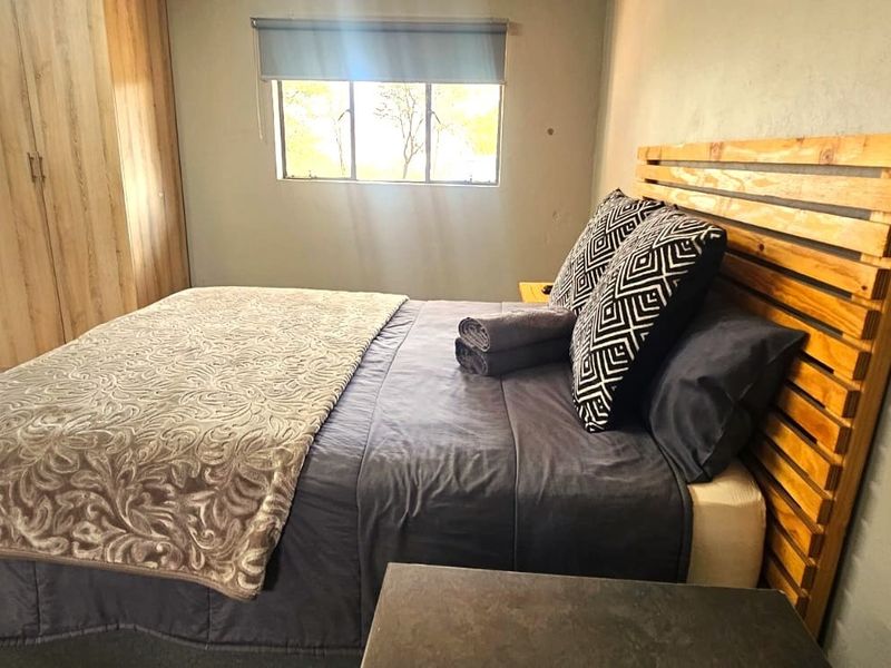 A functional bedroom featuring a built-in wardrobe, a window with a roller blind, and direct access to an outdoor area.
