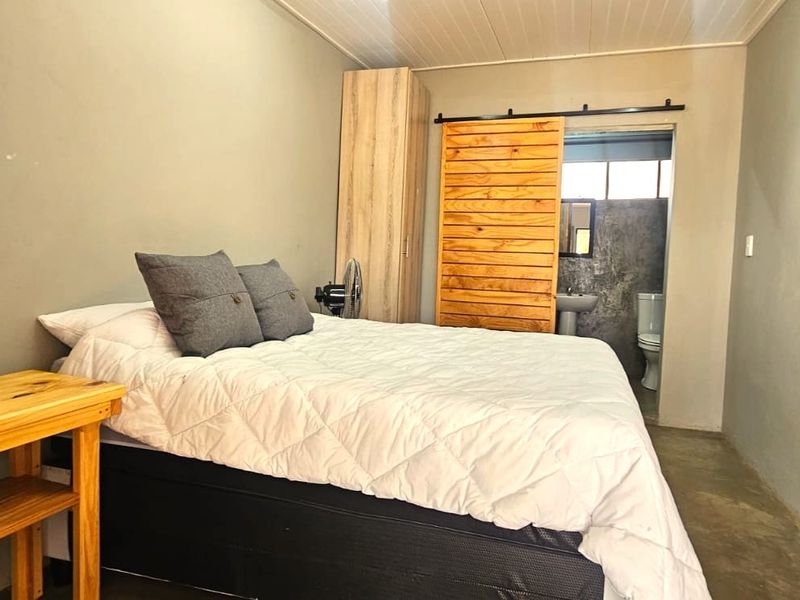 A bedroom featuring concrete flooring, a built-in wardrobe, and a sliding barn door providing access to an en-suite bathroom.