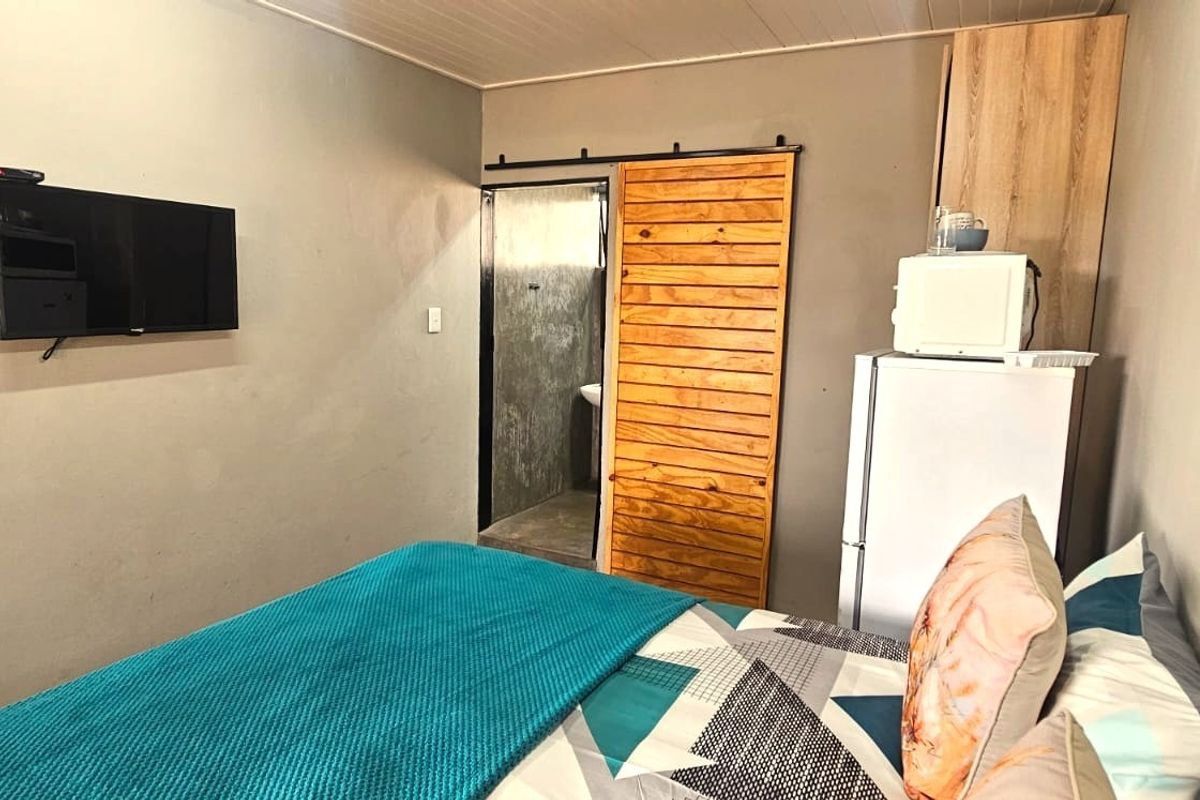 A compact bedroom featuring a sliding wooden barn door, built-in storage cabinetry, and neutral wall finishes.