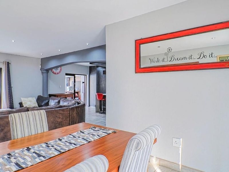 Open-plan living and dining area featuring tiled floors, recessed lighting, and a distinct architectural archway connecting to the kitchen space.