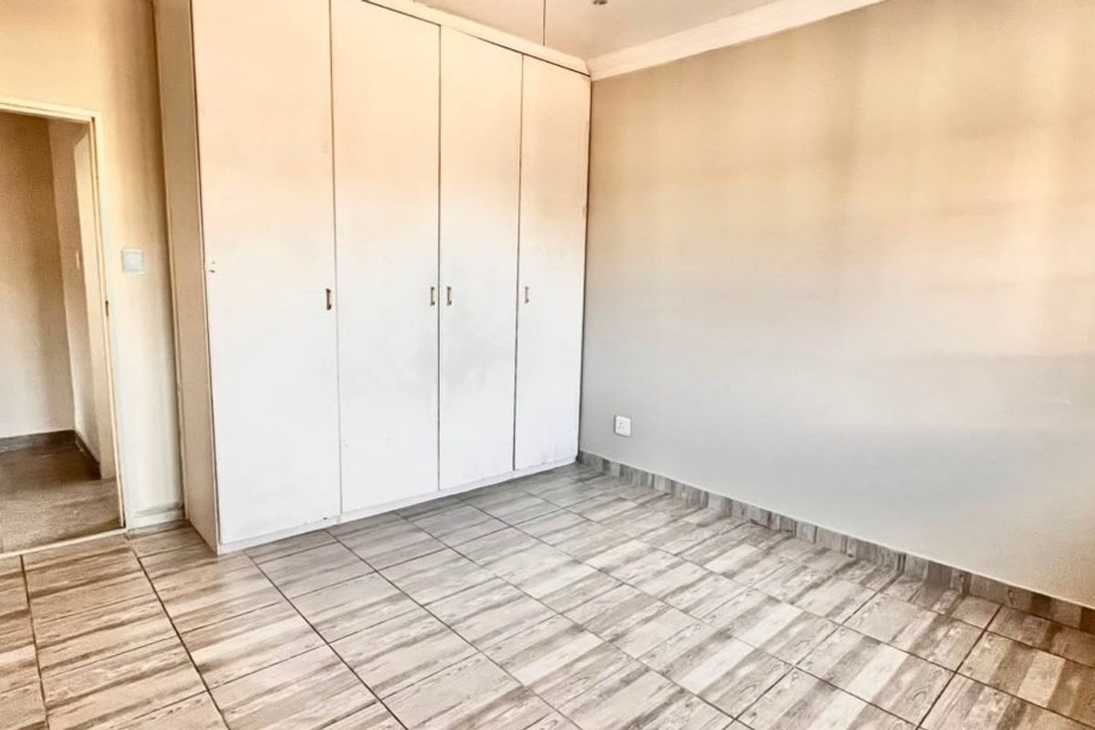 An empty bedroom featuring tiled flooring and built-in cupboards, offering a neutral canvas ready for personalization.