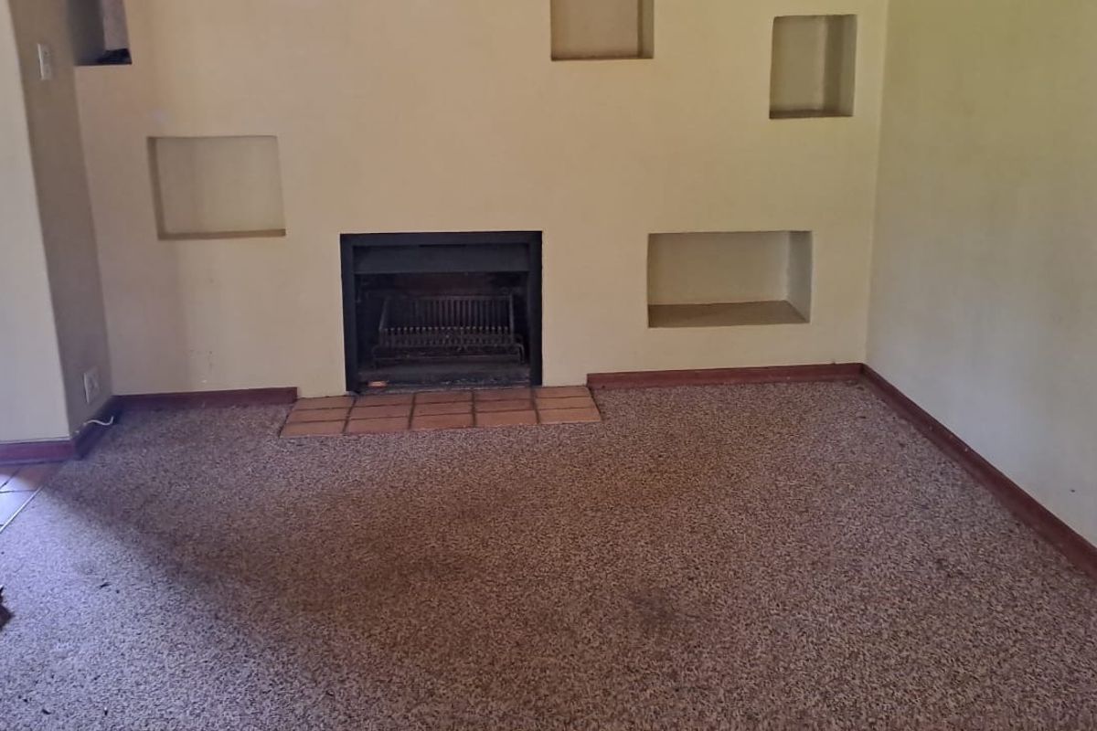 An empty living room featuring a built-in fireplace with a tiled hearth and decorative recessed wall niches.