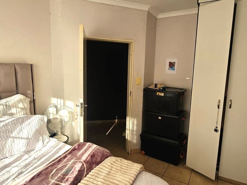 A bedroom featuring tiled flooring, a built-in wardrobe, and coving, offering a functional space with potential for cosmetic updates.