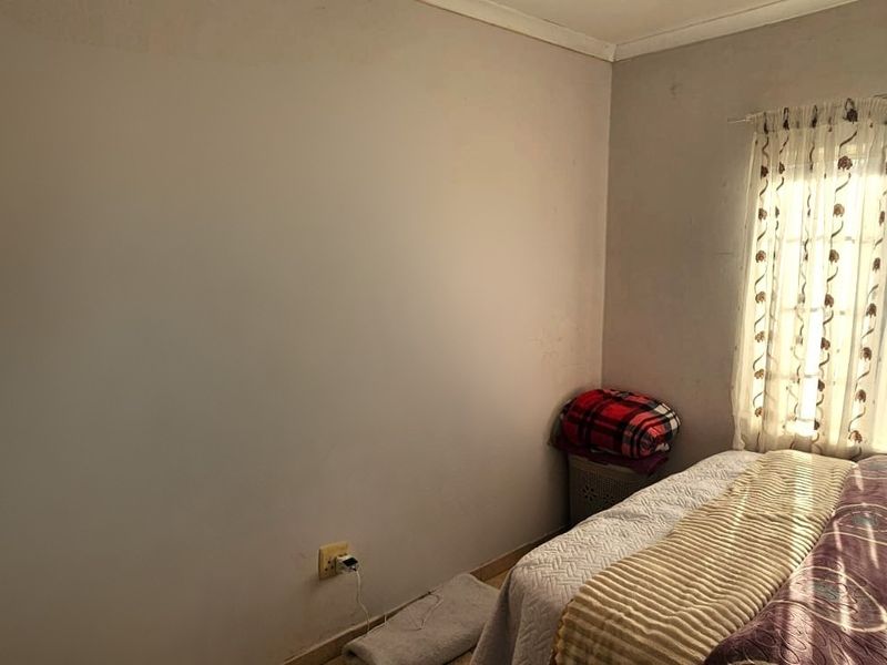 A standard bedroom featuring a window with curtain rails and neutral wall finishes, providing a functional space for rest.