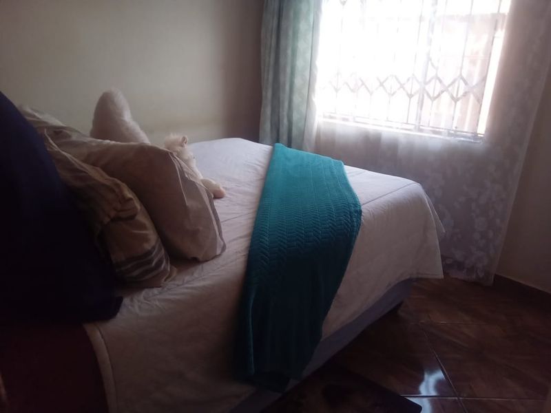 A bedroom featuring tiled flooring and a window fitted with a security gate.