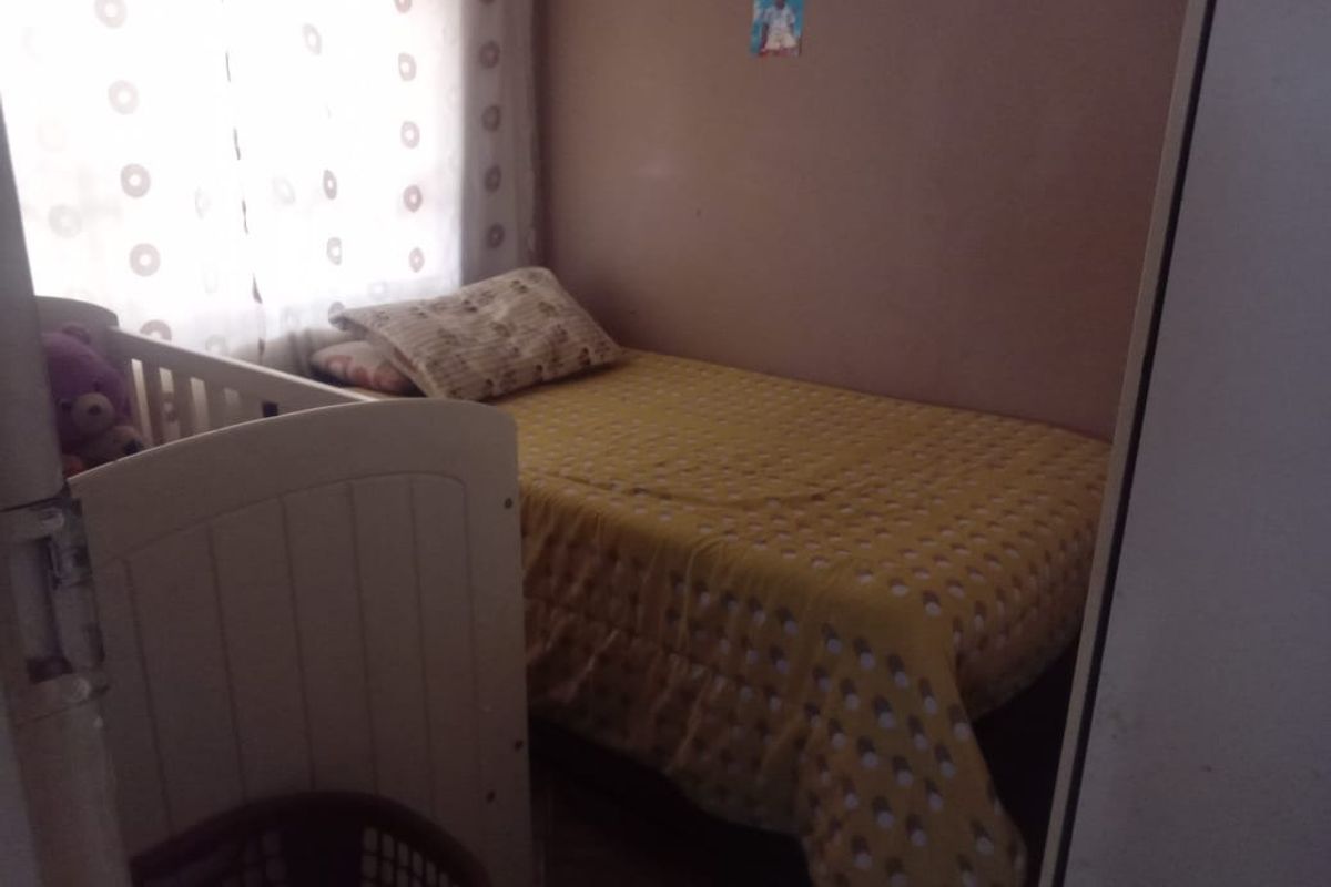 A compact bedroom featuring a built-in cupboard and natural light from the window.