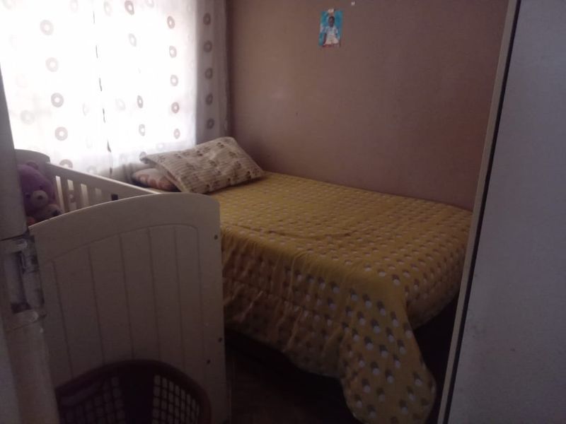A compact bedroom featuring a built-in cupboard and natural light from the window.
