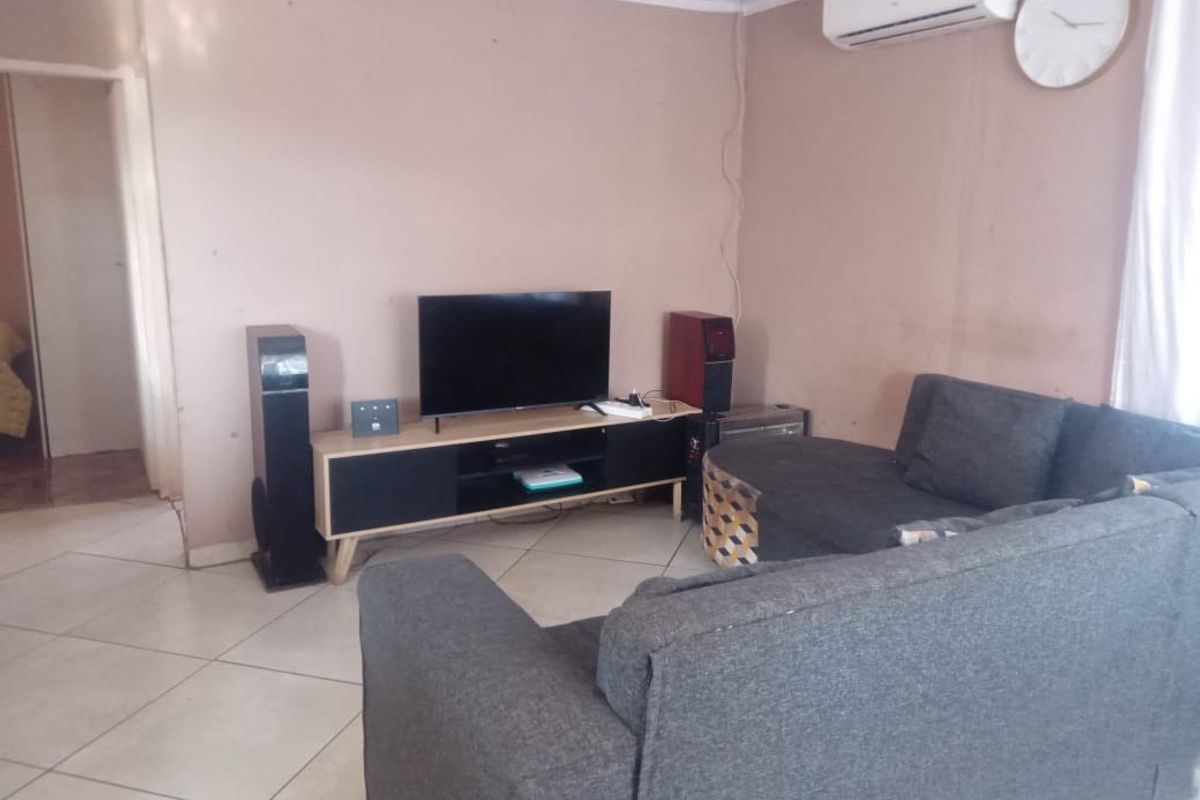 A living room featuring ceramic floor tiles, a wall-mounted air conditioning unit, and coved ceiling cornices.