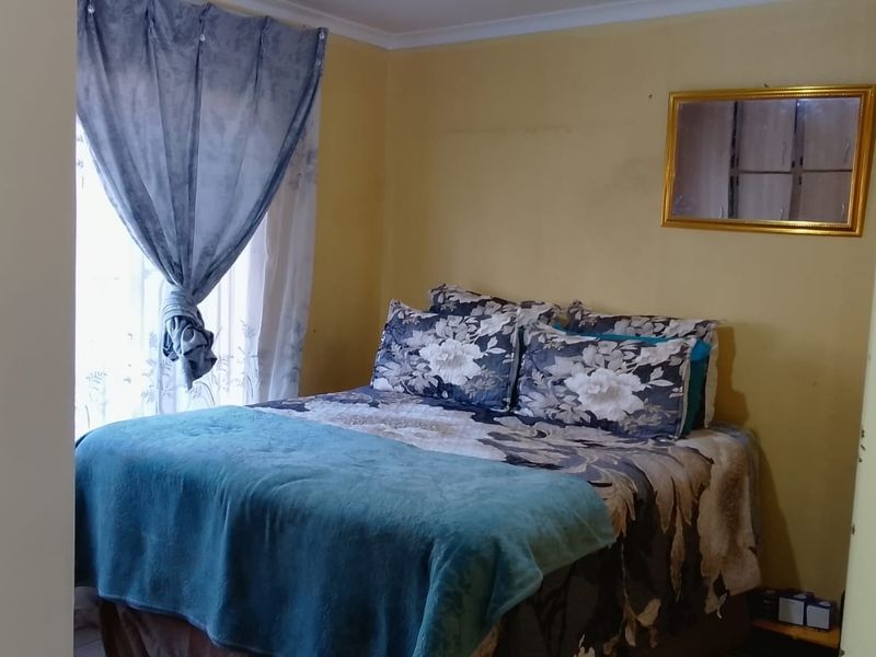 A compact bedroom featuring yellow painted walls and a window with installed curtain rails.