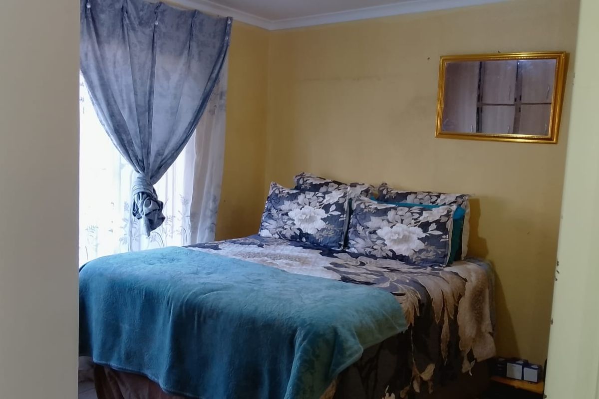 A compact bedroom featuring yellow painted walls and a window with installed curtain rails.