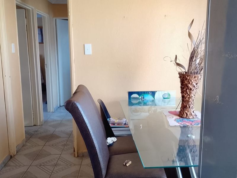 A narrow hallway area featuring tiled flooring and an integrated alarm system keypad, leading towards adjacent rooms.