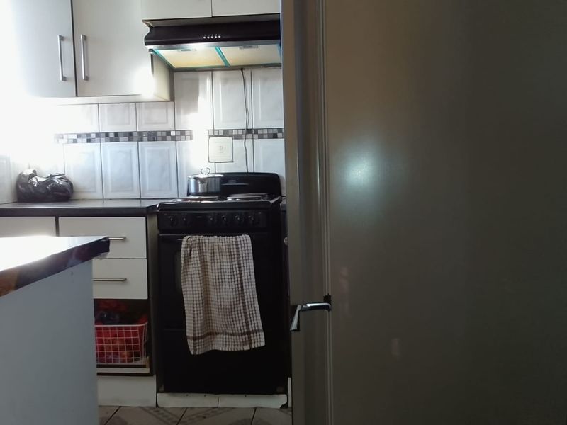 A functional kitchen featuring built-in cabinetry, a stove with an extractor fan, and a tiled backsplash.