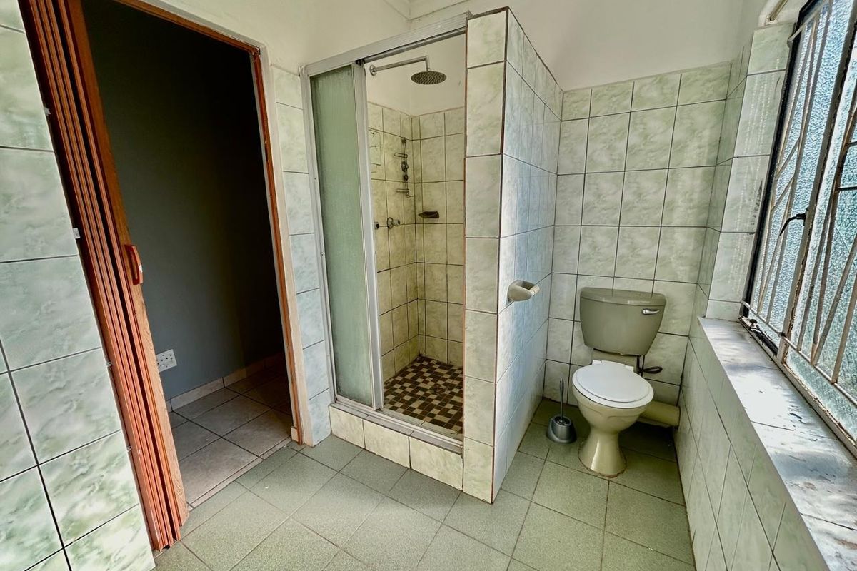A dated bathroom featuring a tiled shower enclosure and standard toilet, requiring modernization of finishes and fixtures to improve functionality and aesthetic appeal.