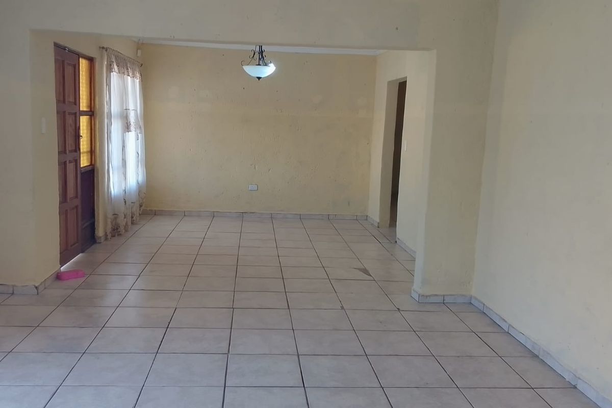 An empty, open-plan living area featuring neutral tiled flooring and a central ceiling light fixture, ready for personalization.