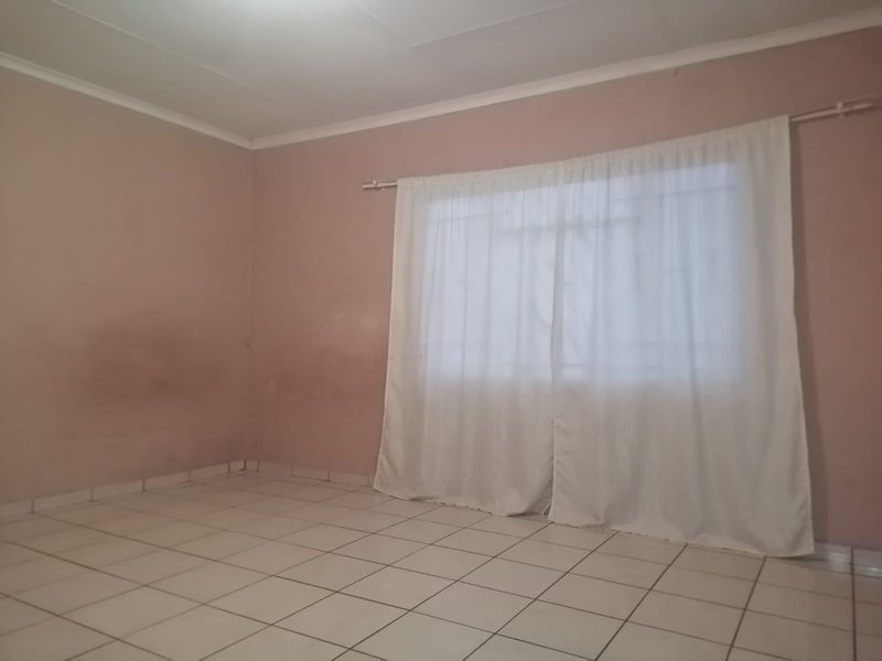 An empty living room featuring tiled flooring and neutral wall finishes, providing a blank canvas for personalization.