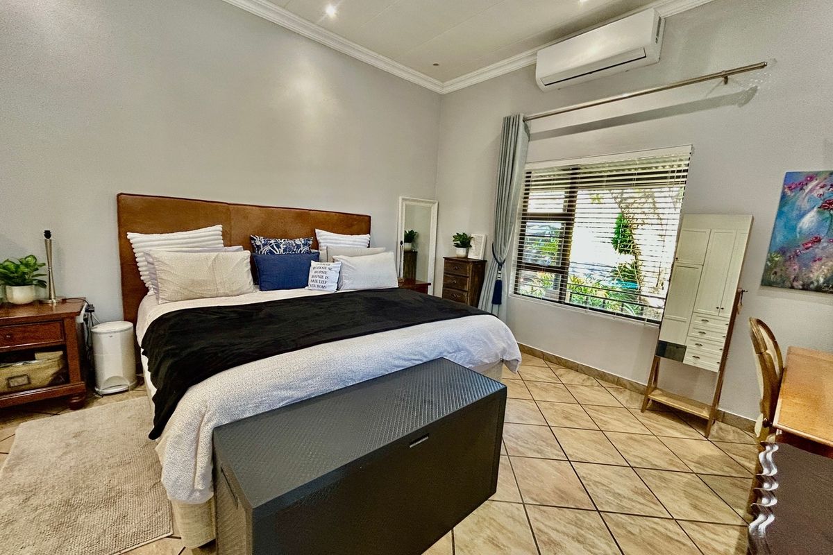 Spacious bedroom featuring tiled flooring, crown molding, recessed lighting, and a wall-mounted split-system air conditioner.