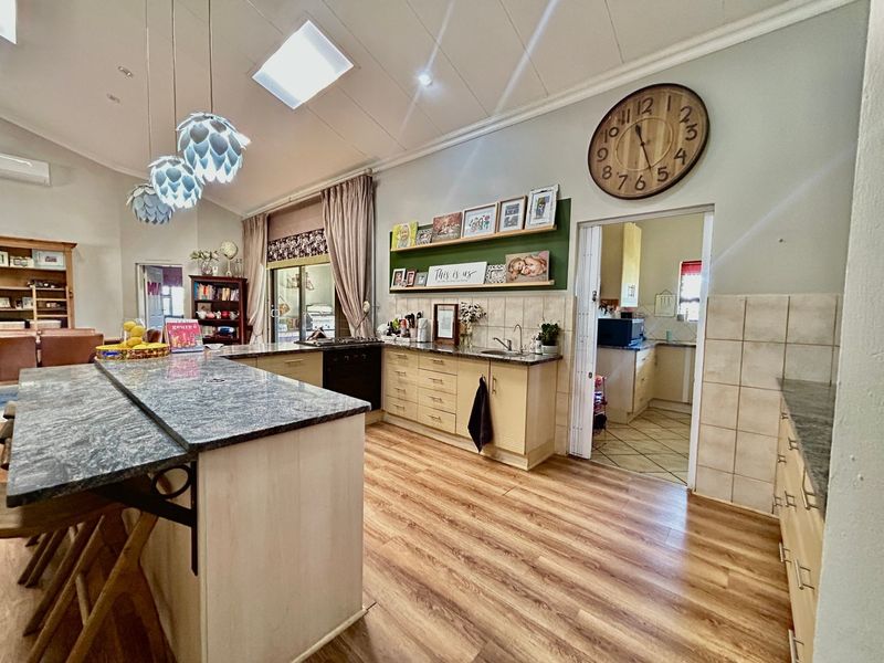 Spacious kitchen featuring a large island with granite countertops, ample built-in cabinetry, a skylight, and direct access to a secondary scullery area.