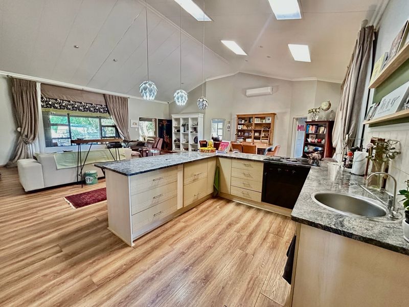 Spacious open-plan living area featuring a modern kitchen with a central island, built-in appliances, and vaulted ceilings with recessed lighting.