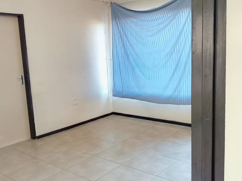 A simple, vacant bedroom featuring neutral tiled flooring and clean white walls, offering a blank canvas for personalization.