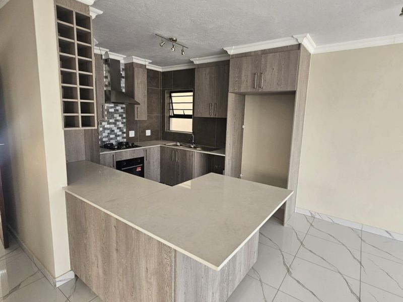 Modern kitchen featuring wood-grain cabinetry, stone countertops, a breakfast bar, built-in oven, gas hob, and elegant marble-look porcelain floor tiles.