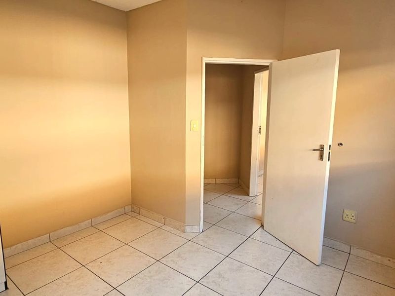 An empty bedroom featuring neutral wall paint, tiled flooring, and built-in cupboards, providing a clean and versatile space.