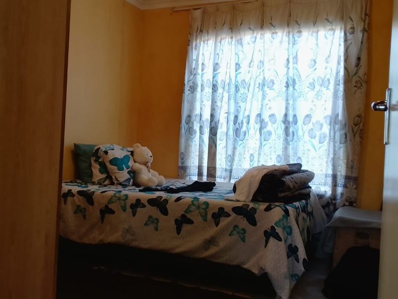 A standard bedroom featuring a built-in cupboard and natural light through a window with curtain rails.
