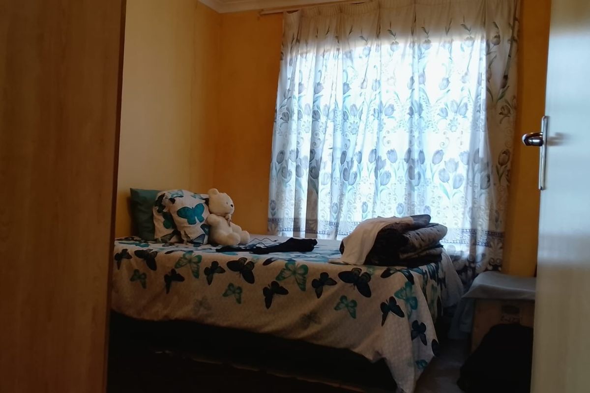 A standard bedroom featuring a built-in cupboard and natural light through a window with curtain rails.