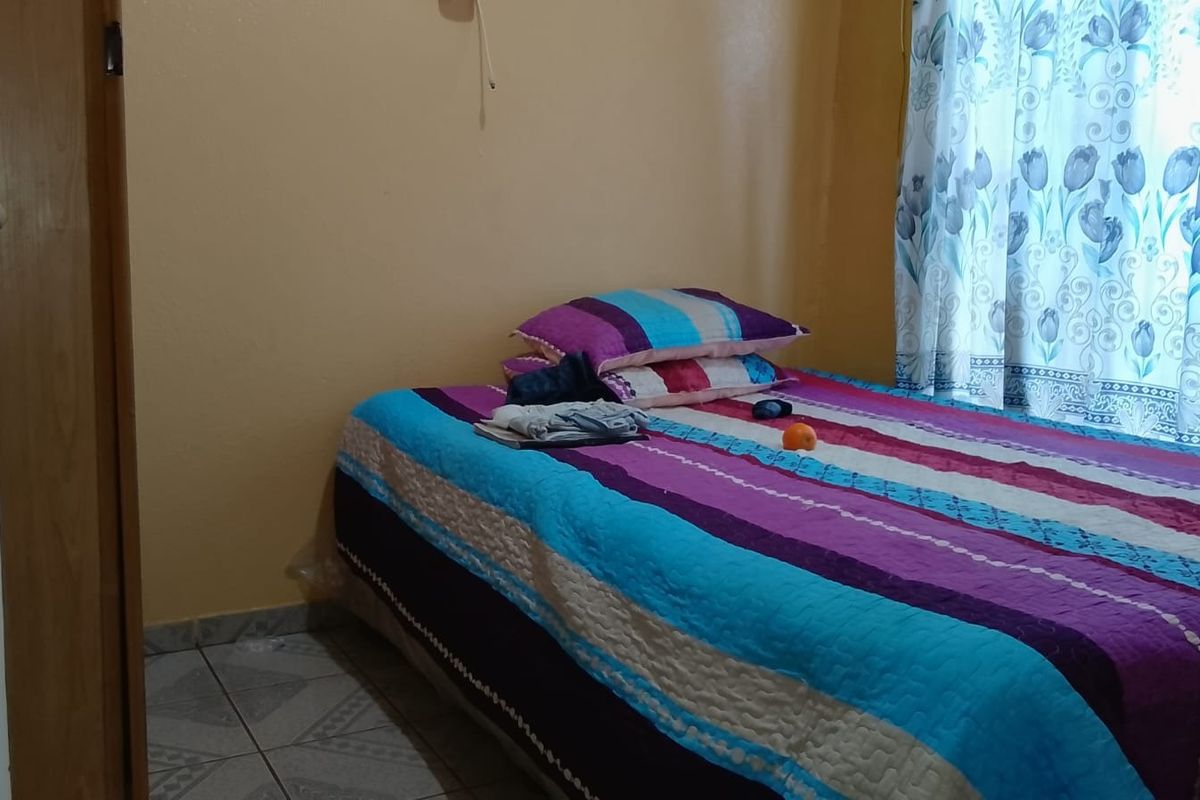 A functional bedroom featuring tiled flooring and a standard internal door, providing a simple and practical living space.