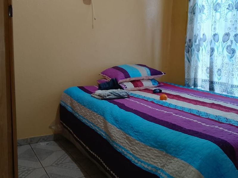 A functional bedroom featuring tiled flooring and a standard internal door, providing a simple and practical living space.