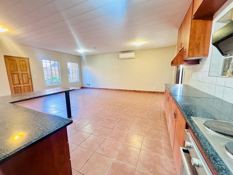 Spacious open-plan kitchen and living area featuring tiled floors, built-in cabinetry with granite countertops, and an integrated electric hob and oven.