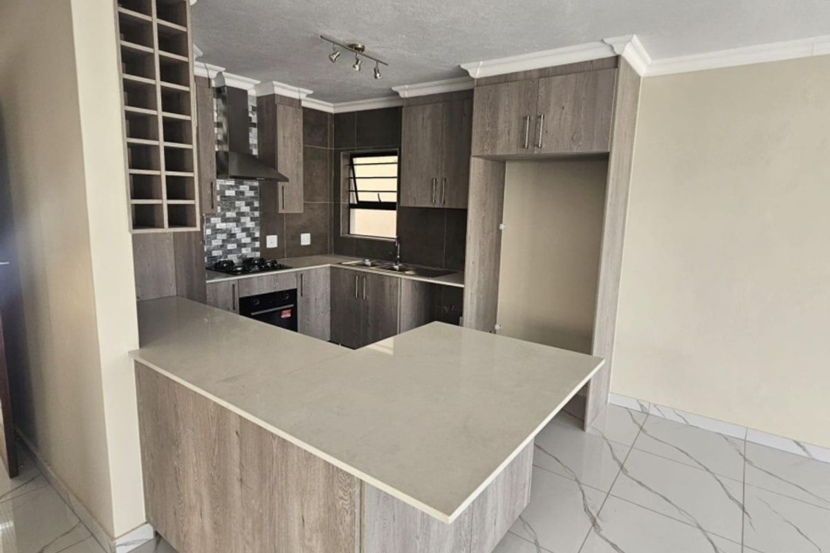 Modern kitchen featuring wood-grain cabinetry, stone countertops, a breakfast bar, built-in oven, gas hob, and elegant marble-look porcelain floor tiles.
