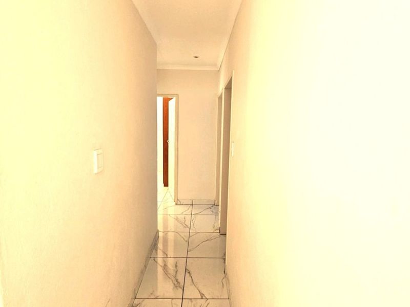 A clean, well-lit hallway featuring modern marble-look floor tiles and neutral wall finishes, providing a bright transition between rooms.