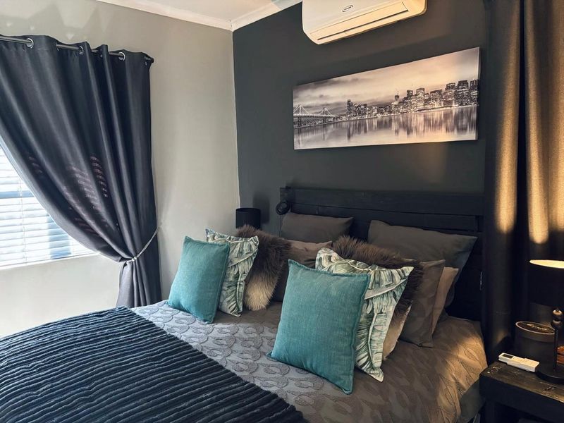 A well-maintained bedroom featuring a dark accent wall, split-system air conditioning unit, and window blinds.