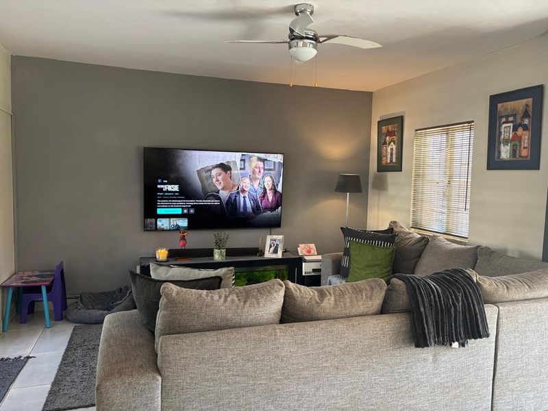 A comfortable living room featuring a ceiling fan and venetian blinds, providing a functional and relaxed space for daily living.