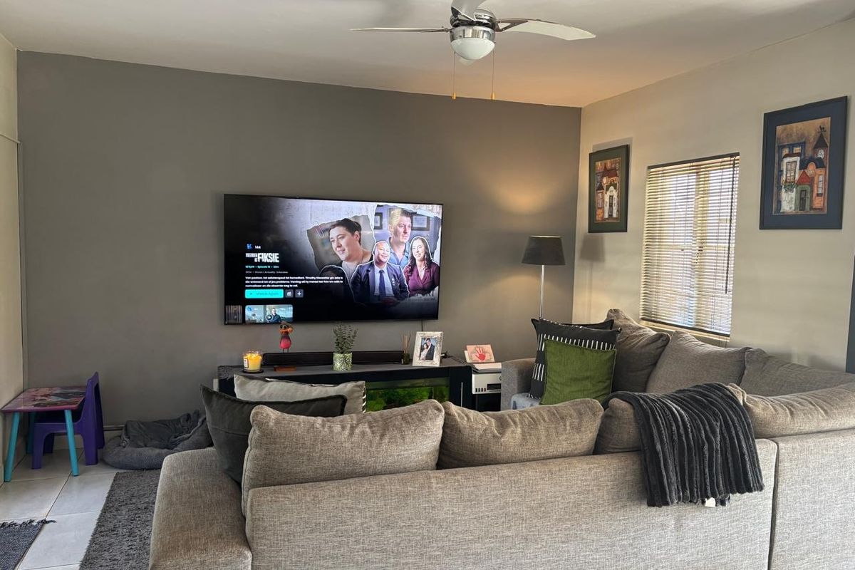 A comfortable living room featuring a ceiling fan and venetian blinds, providing a functional and relaxed space for daily living.