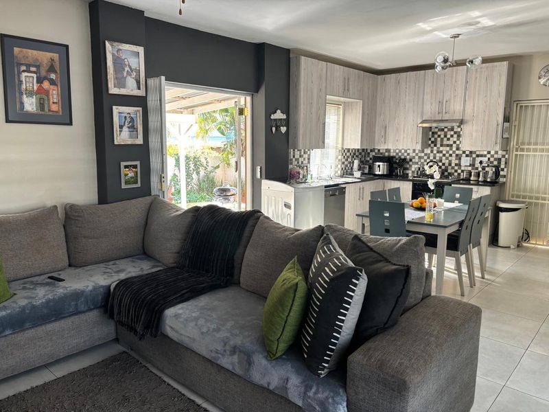 Open-plan living and kitchen area featuring modern cabinetry, a tiled backsplash, and direct access to an outdoor patio through a sliding glass door.