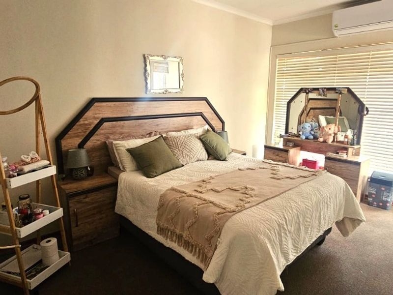 A bedroom featuring a built-in headboard, split-system air conditioning, and venetian blinds, providing a functional and comfortable living space.